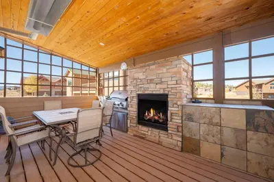 a screened porch with a fireplace and a table and chairs at 67 Fireweed 27A by Stay Winter Park in Tabernash