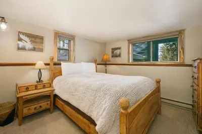 a bedroom with a wooden bed and two windows at 59 Jabberwocky Home by Stay Winter Park in Fraser