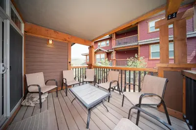 a porch with chairs and a table on a deck at Cozens Pointe Building I Unit I201 by Stay Winter Park in Fraser