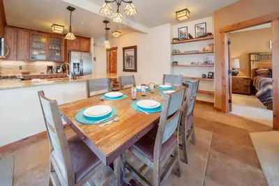 a kitchen and dining room with a wooden table and chairs at Cozens Pointe Building I Unit I201 by Stay Winter Park in Fraser