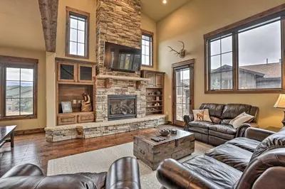 a living room with leather furniture and a fireplace at Luxurious Fraser Townhome with Private Hot Tub! in Fraser