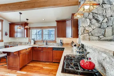 a kitchen with wooden cabinets and a stone wall at Gray Moose in Breckenridge