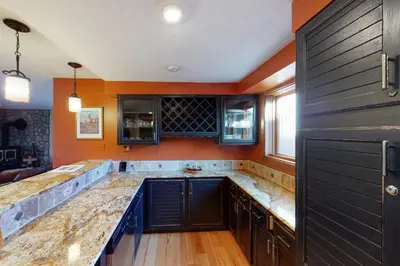 a kitchen with black cabinets and an orange wall at Quaint Mountain Condo in Frisco