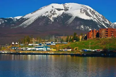 a snow covered mountain next to a body of water at Quaint Mountain Condo in Frisco