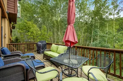 a deck with a table and chairs and an umbrella at Alpine Holidays Ski Tip in Keystone