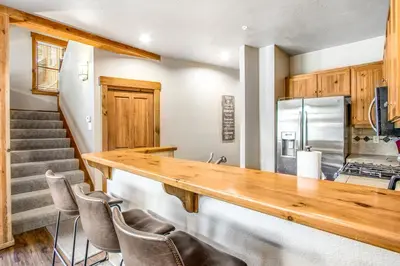 a kitchen with a wooden counter and some chairs at Alpine Holidays Ski Tip in Keystone