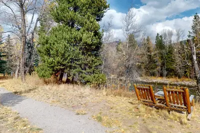 two wooden benches sitting on a path near a lake at Blue River Condo Unit 203 in Silverthorne