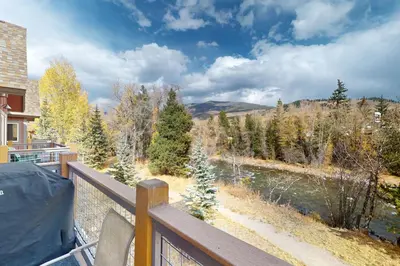 a balcony with a view of a river and trees at Blue River Condo Unit 203 in Silverthorne