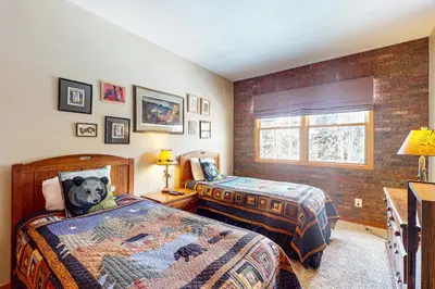 a bedroom with two beds and a brick wall at Northstar Townhome Unit 1968 in Keystone