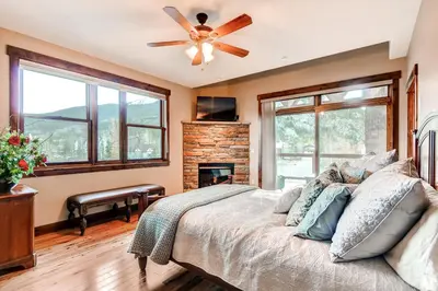 a bedroom with a bed with a ceiling fan and a fireplace at Bears Den Condo Unit 1 in Frisco