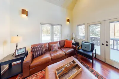 a living room with a brown leather couch and a chair at Wild Flower House in Frisco