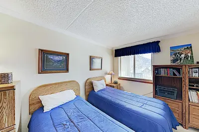 a bedroom with two beds and a book shelf at The Towers Unit 407 in Frisco
