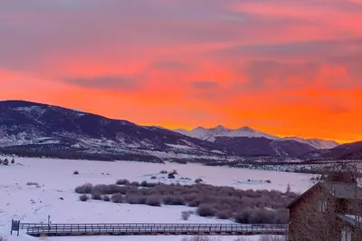 a sunset over a snowy field with mountains in the background at The Towers Unit 407 in Frisco