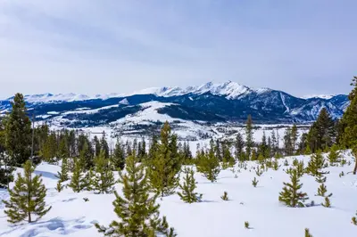 a view from the top of a snowy mountain with trees and mountains at The Towers Unit 407 in Frisco