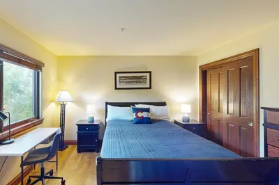 a bedroom with a bed with a desk and a window at Marine Park Condo Unit C-16 in Frisco