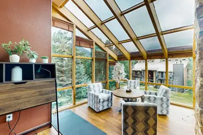 a conservatory with a table and chairs in a room with windows at Marine Park Condo Unit C-16 in Frisco