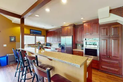 a kitchen with wooden cabinets and a island with bar stools at Marine Park Condo Unit C-16 in Frisco