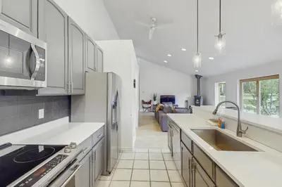 a kitchen with white cabinets and a couch in the background at Mountain Modern Escape in Fraser