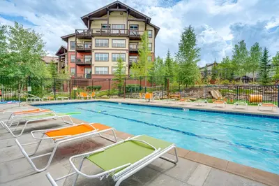 a swimming pool with chairs and a building at Steps to Conquest Ski Lift Granby Home with Grill in Granby