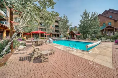 a swimming pool with tables and chairs next to a building at Buffalo Lodge 2 Bed 2 Ba BLCD2 in Keystone