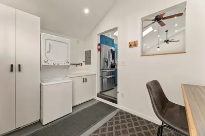 a kitchen with white cabinets and a table and a chair at Vibrant Downtown Bungalow - Walk Everywhere! in Fort Collins