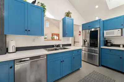 a kitchen with blue cabinets and stainless steel appliances at Vibrant Downtown Bungalow - Walk Everywhere! in Fort Collins