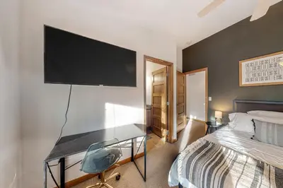 a bedroom with a desk with a television on the wall at Fraser Fantasy in Fraser