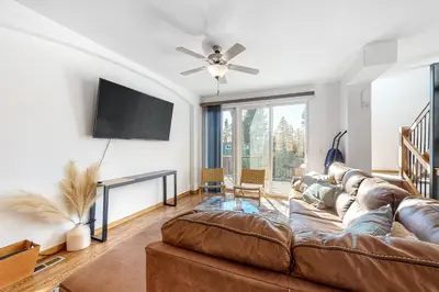 a living room with a brown leather couch and a flat screen tv at Fraser Fantasy in Fraser