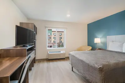 a hotel room with a bed and a flat screen tv at WoodSpring Suites Broomfield-Westminster in Broomfield
