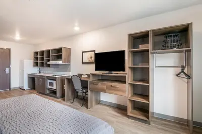 a bedroom with a desk with a television and a refrigerator at WoodSpring Suites Broomfield-Westminster in Broomfield