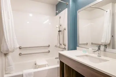 a bathroom with a sink and a tub and a mirror at WoodSpring Suites Broomfield-Westminster in Broomfield