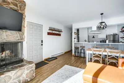 a living room with a fireplace and a kitchen at Condo with Balcony and Views - Steps to Ski Shuttle! in Fraser