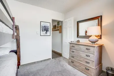 a bedroom with a bed and a dresser with a lamp on it at Condo with Balcony and Views - Steps to Ski Shuttle! in Fraser