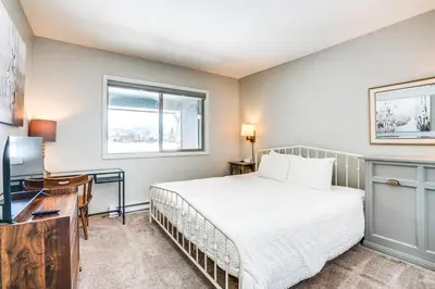 a bedroom with a bed and a desk and a window at Condo with Balcony and Views - Steps to Ski Shuttle! in Fraser