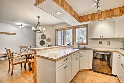 a kitchen with white cabinets and a dining table at Sunny Alpine Escape with Hot Tub and Mountain Vistas! in Fraser