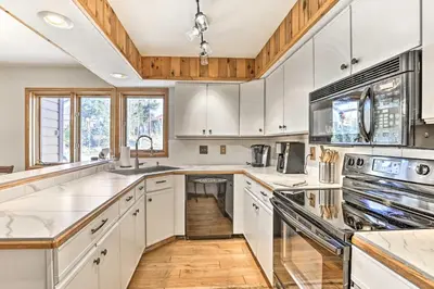 a kitchen with white cabinets and stainless steel appliances at Sunny Alpine Escape with Hot Tub and Mountain Vistas! in Fraser