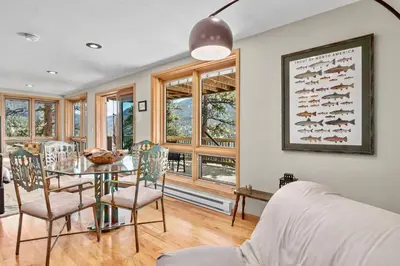 a dining room with a table and chairs and windows at Solitude Vacation Home at Windcliff home in Estes Park