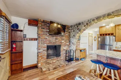a living room with a brick fireplace and a kitchen at Hi Country Haus 14-5 in Winter Park