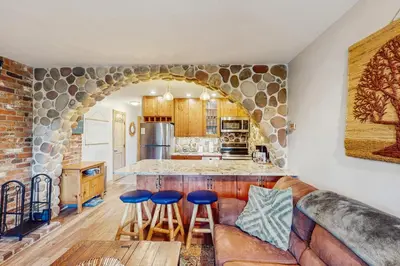a living room with a couch and a stone wall at Hi Country Haus 14-5 in Winter Park