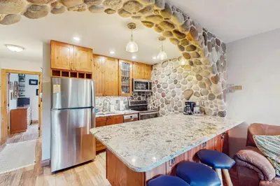 a kitchen with a granite counter top and a stone wall at Hi Country Haus 14-5 in Winter Park
