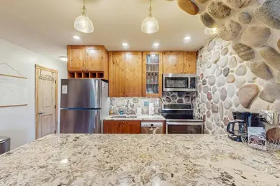 a kitchen with a granite counter top and a stone wall at Hi Country Haus 14-5 in Winter Park