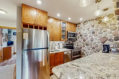 a kitchen with a stainless steel refrigerator and wooden cabinets at Hi Country Haus 14-5 in Winter Park