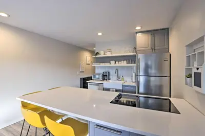a kitchen with a large white counter and yellow chairs at Walk to Main St Frisco! Modern Unit 7 Mi to Slopes in Frisco