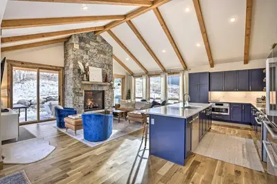 an open kitchen and living room with a stone fireplace at 13 Mi to Slopes! Silverthorne Home with Pool Access in Silverthorne