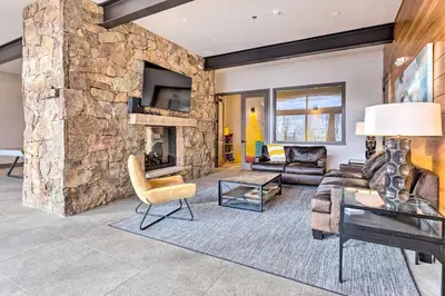 a living room with a large stone wall at 13 Mi to Slopes! Silverthorne Home with Pool Access in Silverthorne