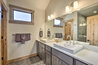 a bathroom with two sinks and a large mirror at 13 Mi to Slopes! Silverthorne Home with Pool Access in Silverthorne