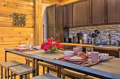a wooden table with plates and cups and flowers on it at 2 Mi to Skiing Studio with Pool Access in Granby! in Granby