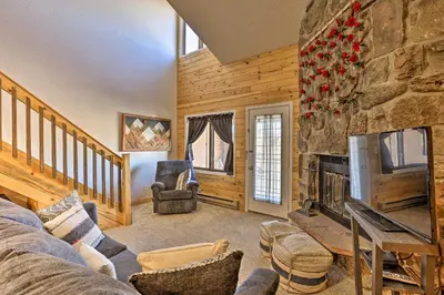 a living room with a fireplace and a stone wall at 2 Mi to Skiing Studio with Pool Access in Granby! in Granby