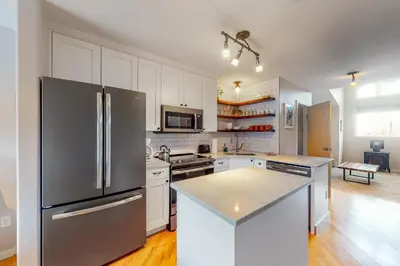 a kitchen with white cabinets and a stainless steel refrigerator at At the Crossroads in Frisco