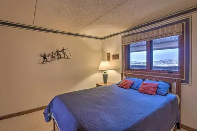 a bedroom with a blue bed and a window at 7 Mi to Keystone Resort Condo with Hot Tub and Pool in Dillon
